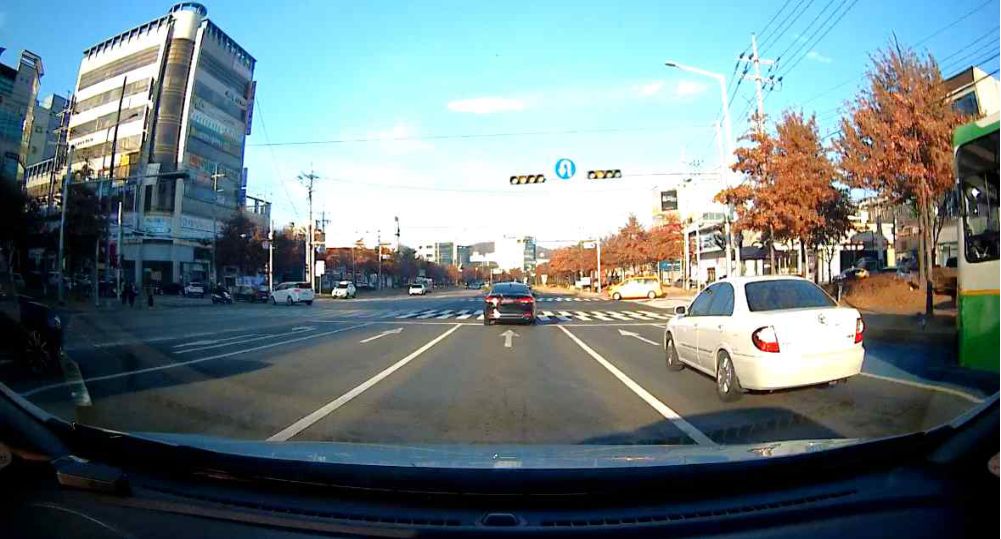 Vehicle signal is yellow (about to turn red) · U-turn sign ahead · In lane 3, white car in lane 4, bus in lane 5 · Crosswalk ahead