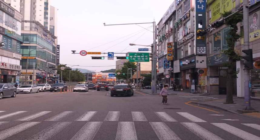 Road in front of shops with heavy traffic · Pedestrian jaywalking ahead
