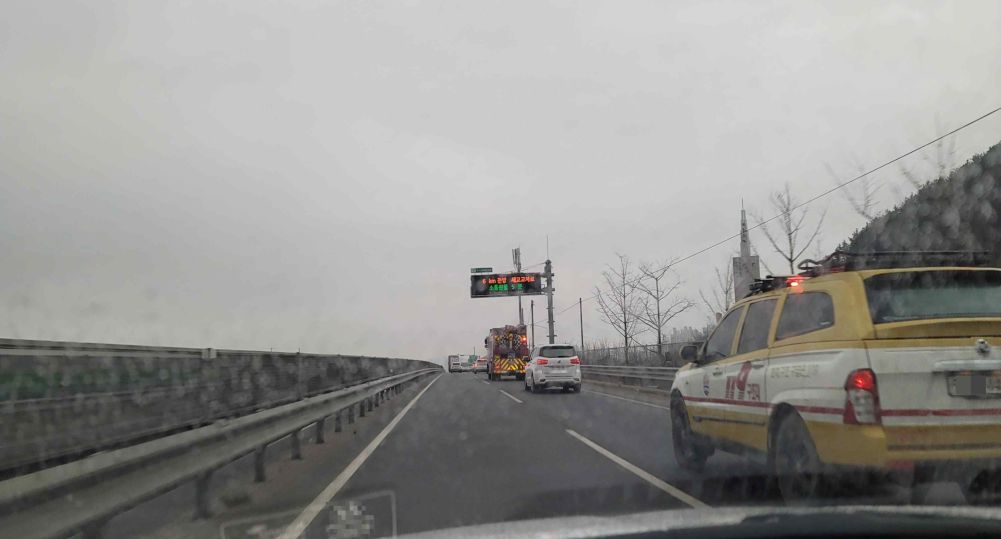 Road with two lanes in each direction · Road surface wet from rain · Fire truck on an emergency call in lane 2
