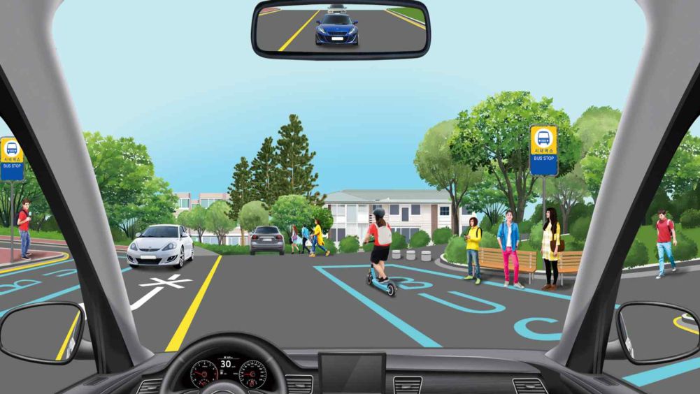 Many pedestrians walking on the roadway · Cars following behind on the right