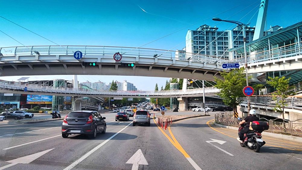 Oldingi transport svetoforida yashil chiroq va chapga yashil strelka yongan · Pandus bilan ulangan piyodalar ko'prigi o'rnatilgan