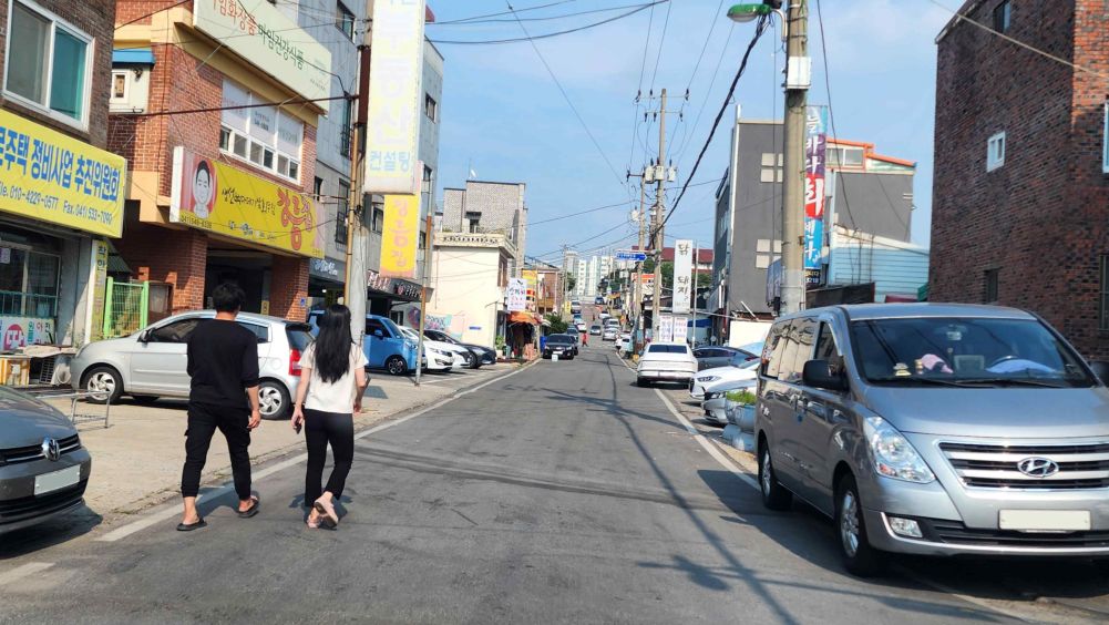 Back street around shops · Road with no separation between sidewalk and roadway · A pedestrian is walking ahead on the left