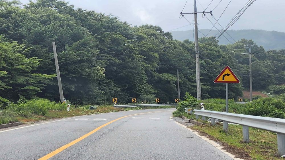 向右弯曲的下坡道路 · 路面多处散落沙子和泥土