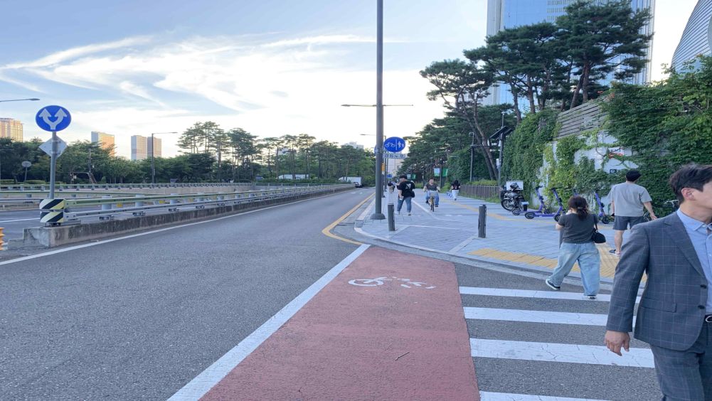 T-shaped (ㅏ-shaped) intersection · Crosswalk and bicycle crossing installed · Pedestrians crossing the crosswalk · Shared bicycle-pedestrian path sign ahead · A cyclist approaching on the shared bicycle-pedestrian path